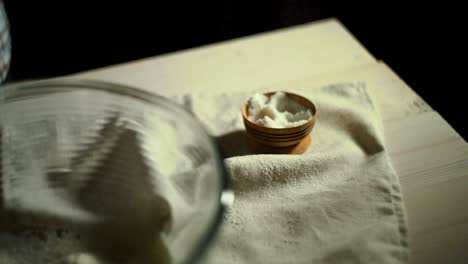 chef hand sprinkling salt into glass bowl. chef seasoning food