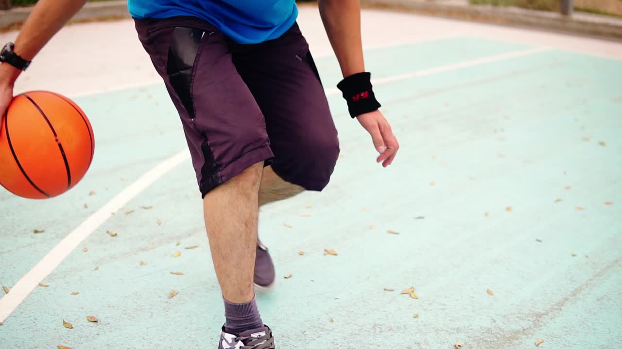 Close up view of a young man practicing basketball outside. Slow Motion shot