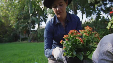 Caucasian-lesbian-couple-wearing-hats-gardening-together-in-the-garden