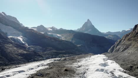 Aerial-view-of-the-Matterhorn-over-the-moraines-and-crevasses-of-the-Gorner-glacier-on-a-sunny-summer-day-in-Zermatt,-Switzerland