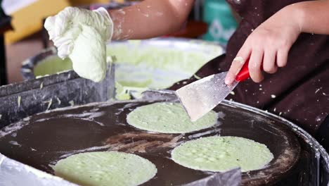 person cooking green pancakes on a griddle