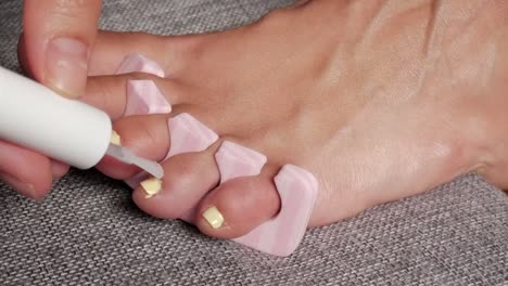 close-up of a pedicure with yellow polish on toes indoors