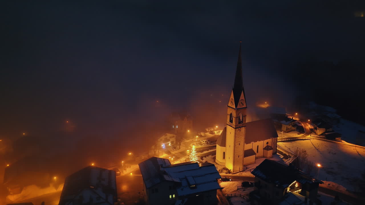 Aerial drone view of the San Lorenzo Church illuminated at night in the Selva di Cadore comune in Dolomites, Italy