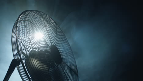 fan blades rotate in rays of light and fog