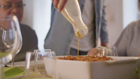 unrecognizable adult man pouring sauce into dish and grandpa watching it during family dinner at home 1