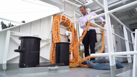 Capitán-Preparando-La-Cuerda-De-Amarre-A-Bordo-Para-Su-Uso-A-Bordo-Del-Barco-De-Pasajeros---Clip-Estático-De-ángulo-Bajo-De-La-Persona-Que-Desenrolla-La-Cuerda-De-La-Posición-De-Almacenamiento