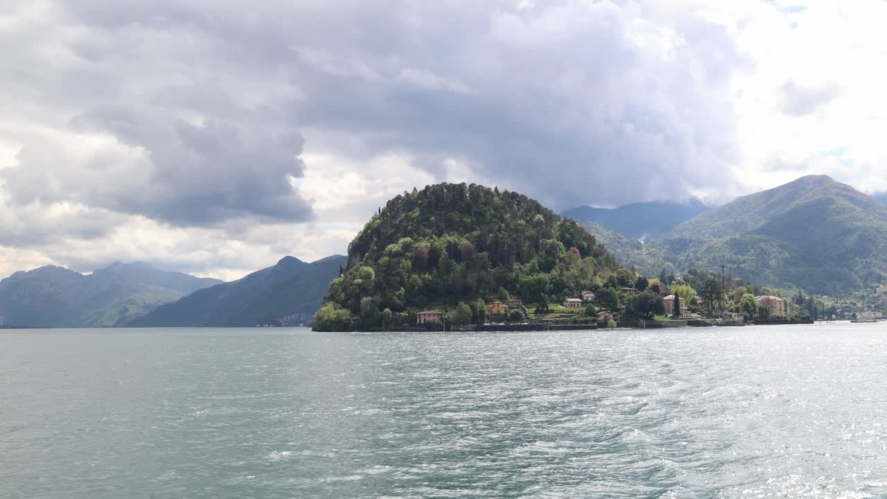 Crossing lake Como, green landscape and mountains in the distance