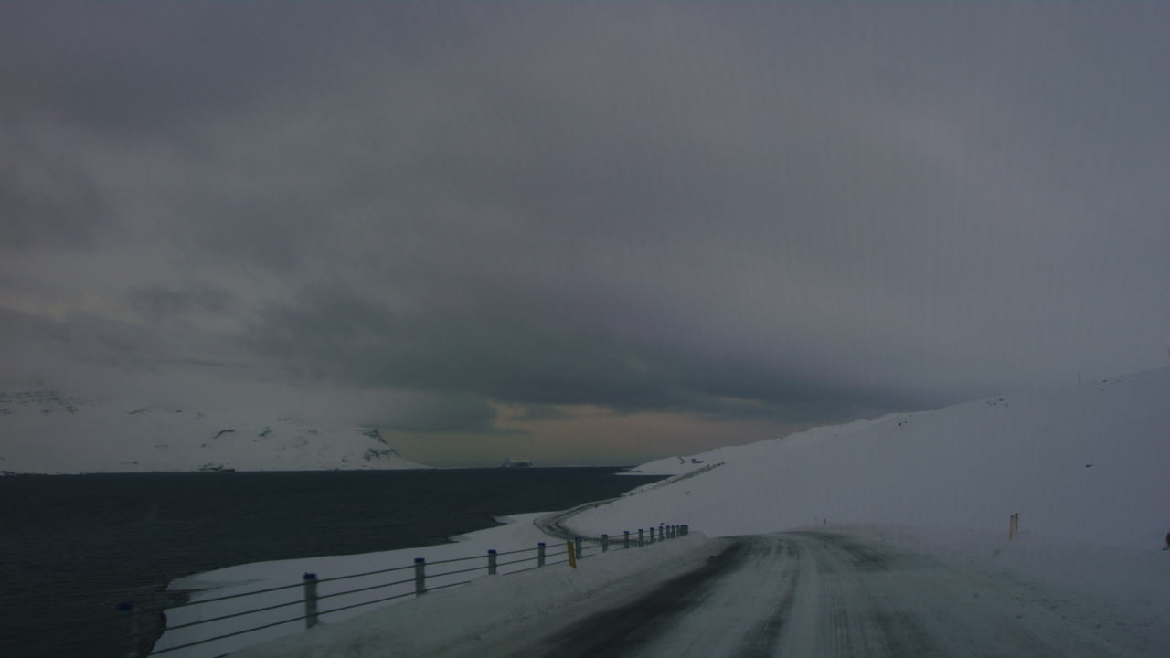 Winter drive through desolate icy roads surrounded by snow-covered Arctic tundra in Iceland