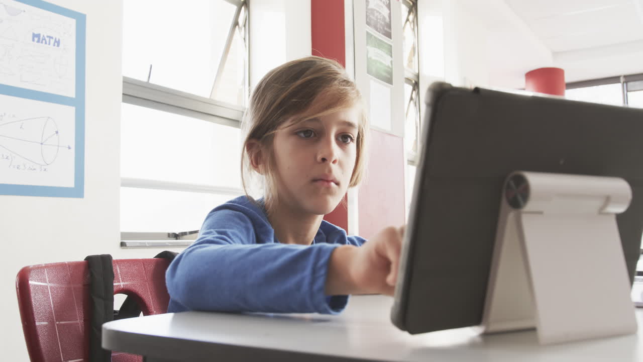 In school, boy using tablet in classroom, focusing on learning