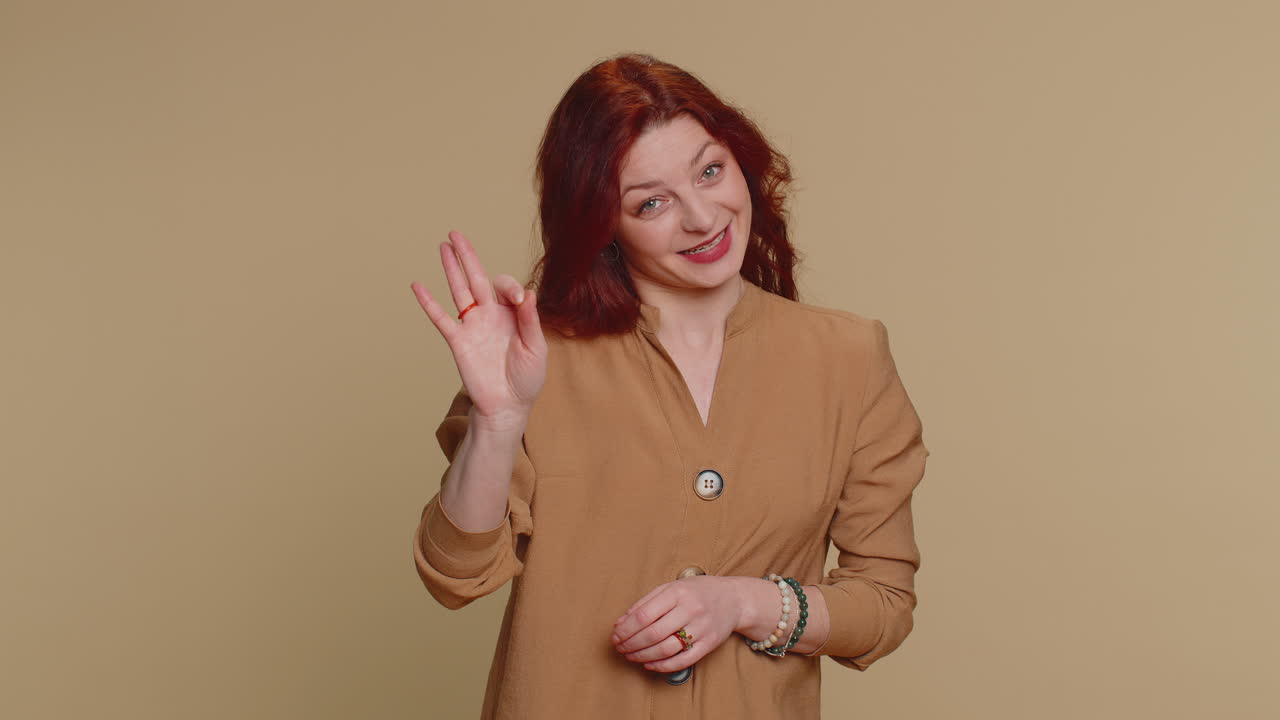 여성은 긍정적으로 보이며,  ⁇ 을 보여줍니다. 긍정적 인 무언가를 표시하는 것과 같은 피드백 제스처를 승인합니다.