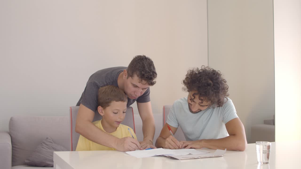 los padres ayudan al hijo con la tarea de escritura