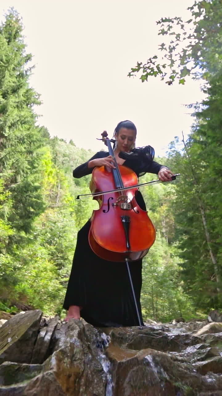 Attractive woman with cello. Female musician plays on cello against picturesque landscape