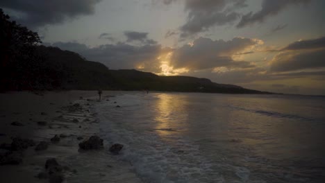 Deslizándose-Por-Una-Playa-Hacia-Una-Hermosa-Puesta-De-Sol-Mientras-Las-Olas-Chocan-Contra-La-Playa-En-Cámara-Lenta