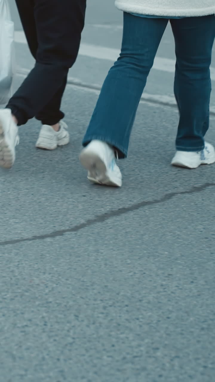A close view capturing the feet of people walking across the road, with camera focusing on lower body and footwear