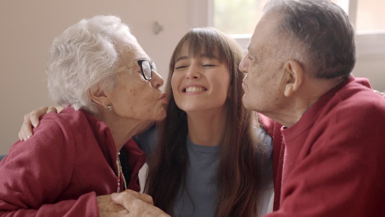 Grandparents kissing their granddaughter while she visits in a geriatric