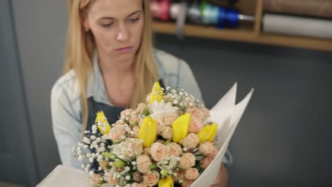 Junge-Blonde-Floristin,-Die-Einen-Blumenstrauß-In-Dekorationspapier-Einwickelt