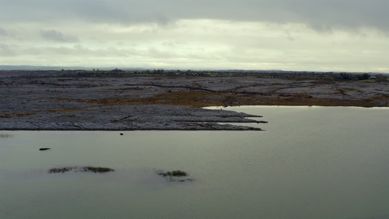 Aerial parallax shot of Burren landscape with seasonal lake in the foreground. Ireland.