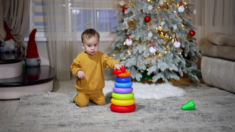 toddler playing with stacking rings near christmas tree