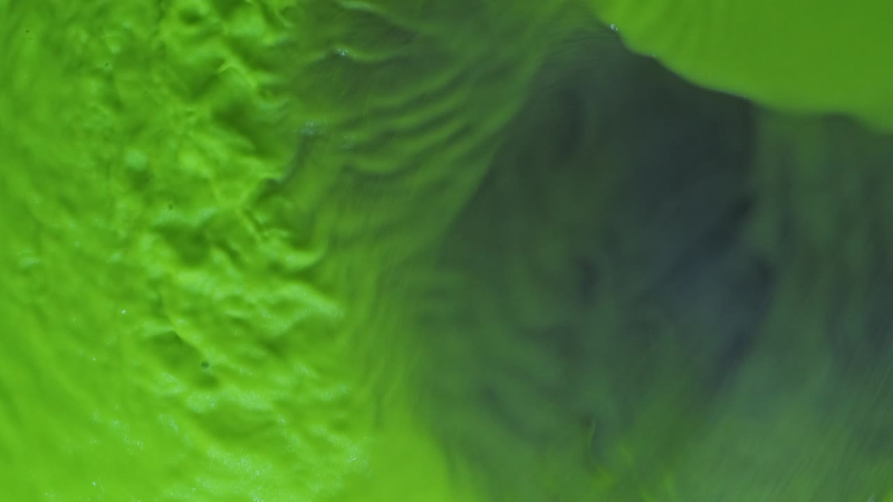 ondas abstractas de pintura de neón verde sobre un fondo azul. vista desde arriba.