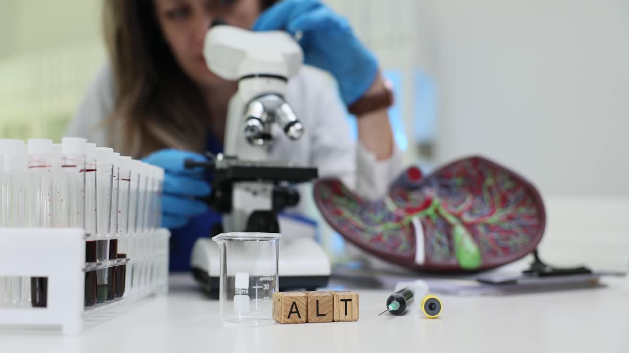 A medical professional conducting laboratory tests with a microscope, blood samples, and a liver model