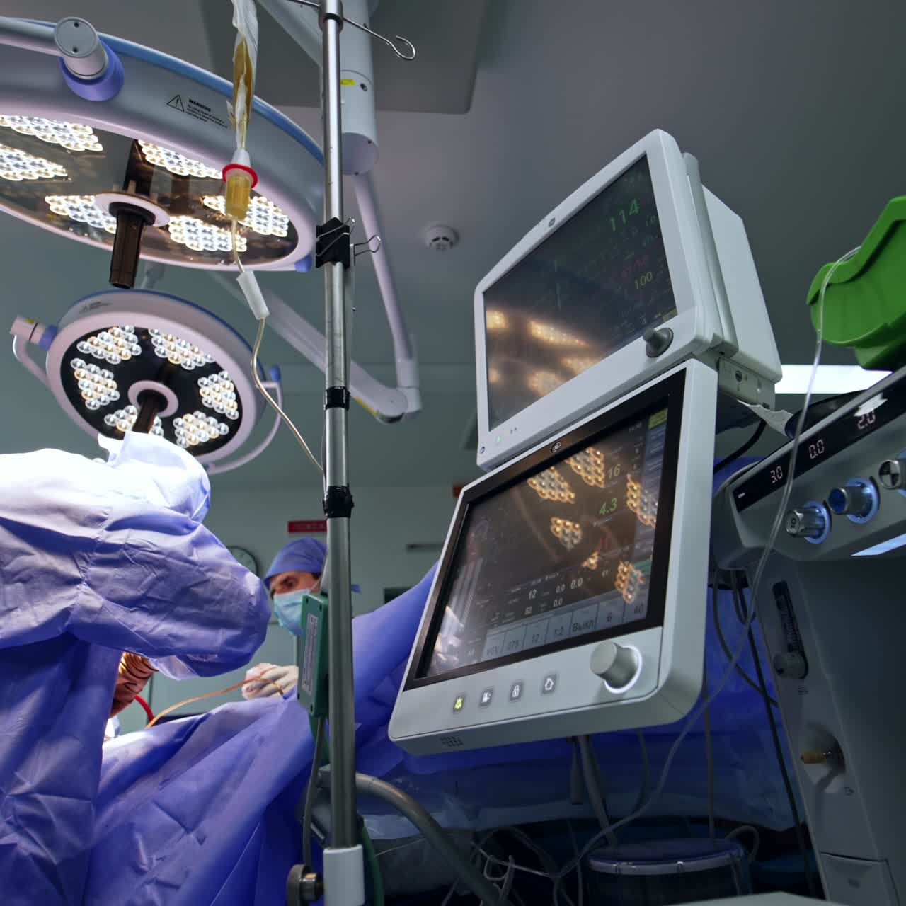 Up-to-date surgery room with neurosurgical procedure in progress. Lung ventilating machine is at foreground. Surgical team works at backdrop. Low angle view