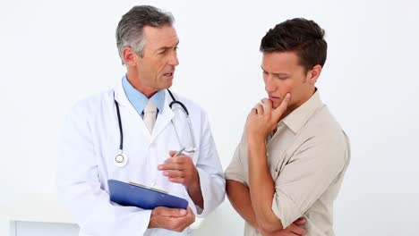 Patient-speaking-to-his-doctor-holding-clipboard