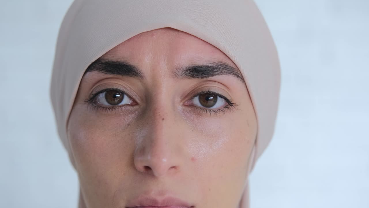 zoom en retrato de encantadora mujer musulmana en hijab beige, poderosos ojos atractivos mirando a la cámara. la mirada de ojos marrones con cejas negras, una mujer segura con un temperamento fuerte