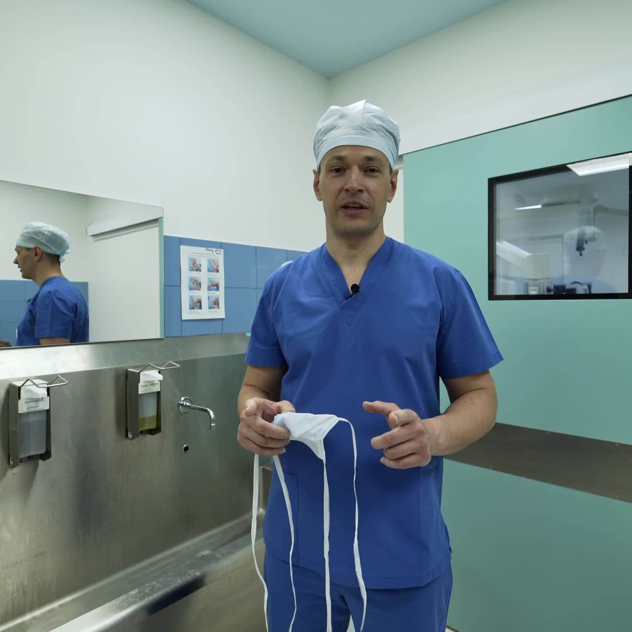 Caucasian surgeon leaving the modern surgery room. Handsome tall medical professional talks to camera in pre-operational room