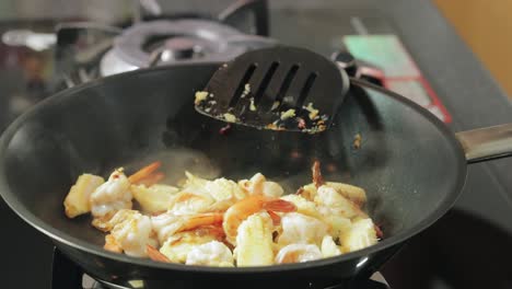 Una-Mujer-Está-Agregando-Salsa-De-Soja-Ligera,-Salsa-De-Ostras-Y-Azúcar-A-Los-Camarones-Fritos,-Preparando-Camarones-Fritos-Picantes-Con-Menú-De-Albahaca---Receta-Tailandesa