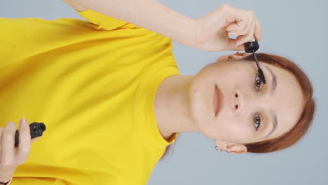 Vertical-video-of-Woman-is-applying-mascara-to-her-eyes.