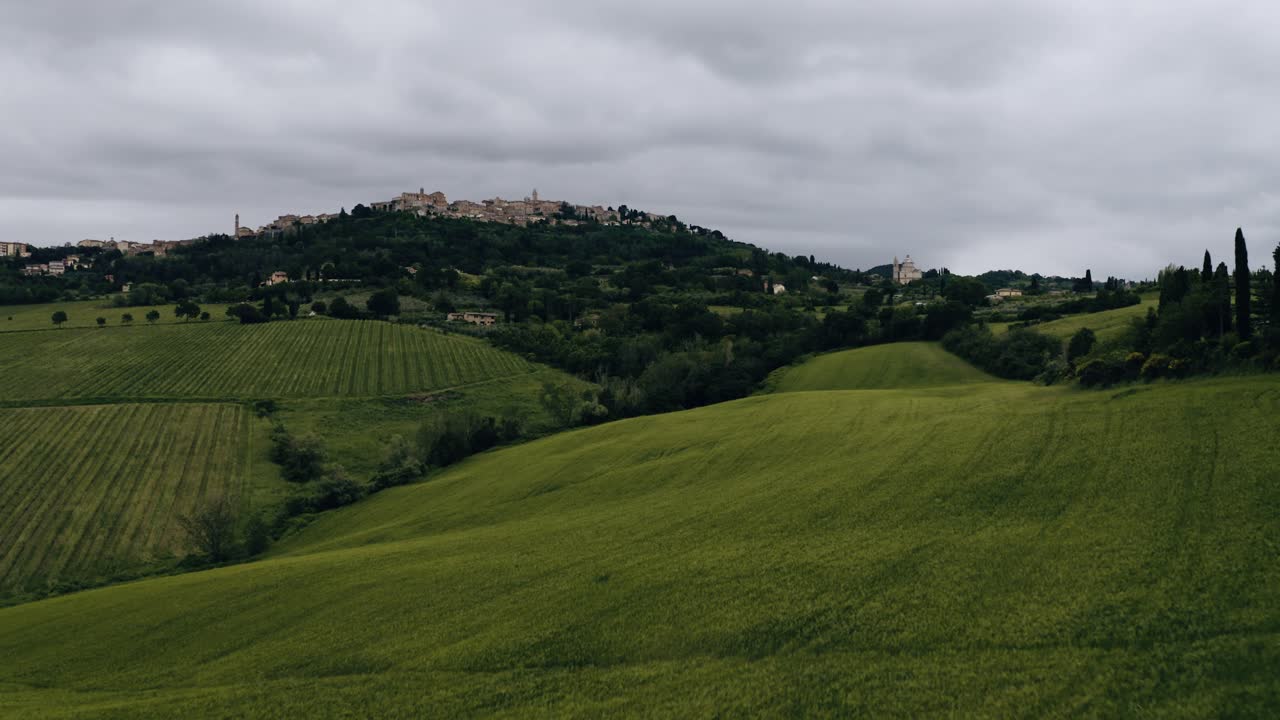 Low drone shot soaring over Italy's rural countryside filled with green fields