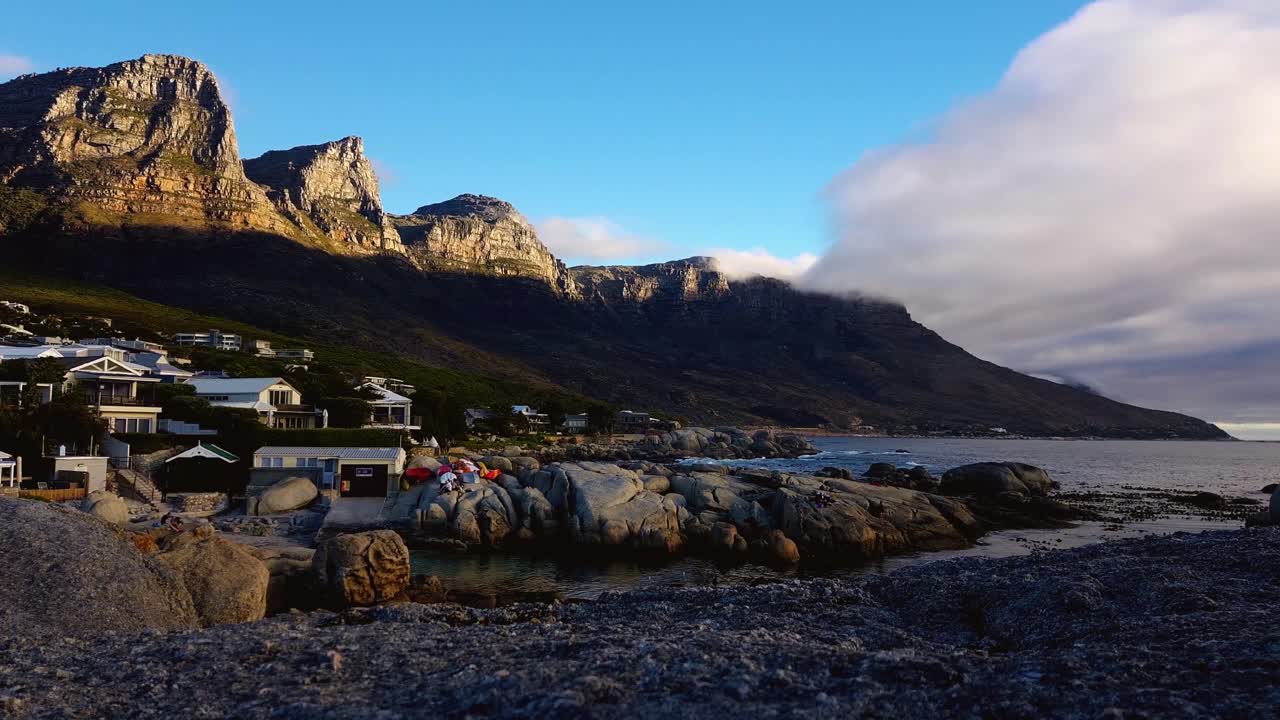Fast paced clouds - ocean waves moving in on resort at the base of South African Apostles Mountain range.