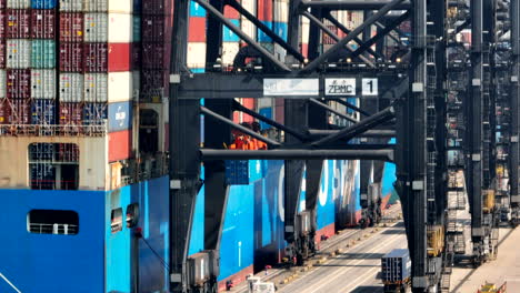 gantry crane loading a blue container on a vessel