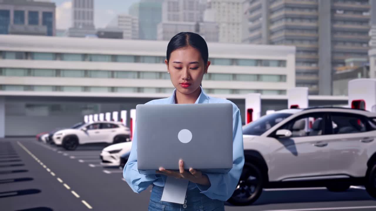 Asian Female With Her Laptop, Electric Vehicles Charging at Modern City Station, She Observes By Looking Around Before She Come To Concentrating With Her Laptop