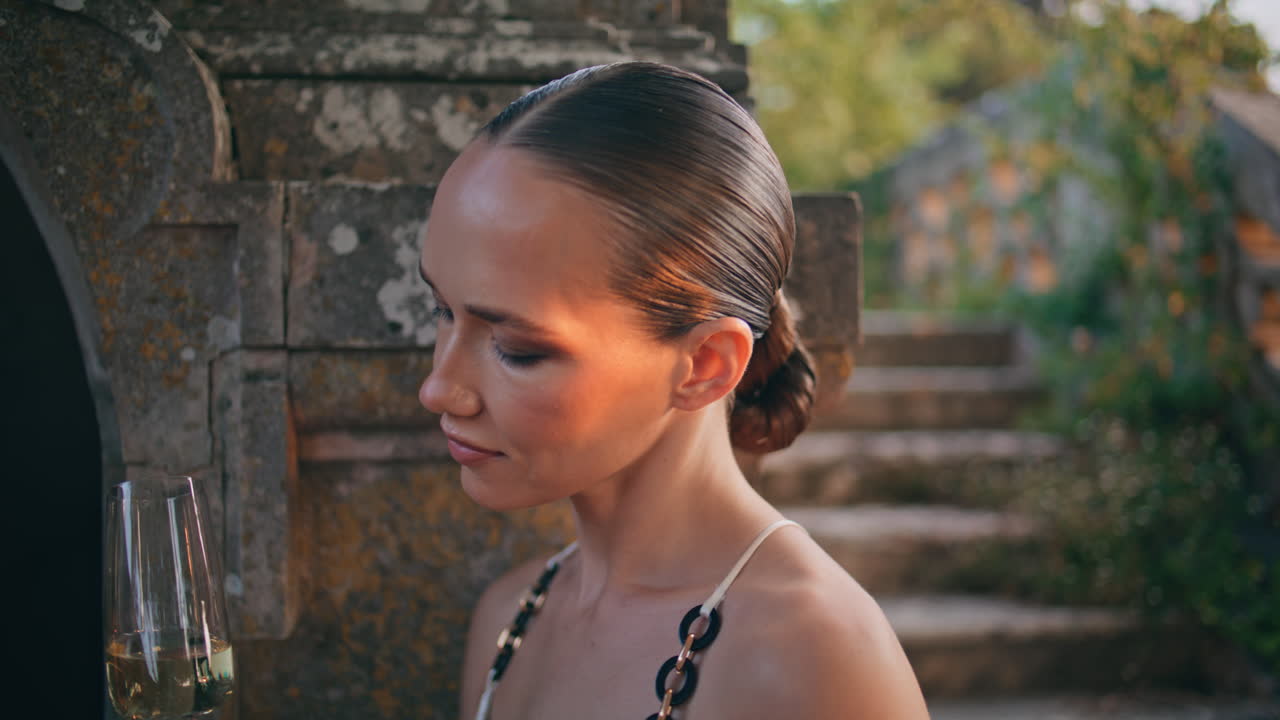 멋진 여자가 중세 성에서 유리 컵에서 페인을 즐기고 있습니다.