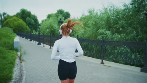 woman running in park with headphones