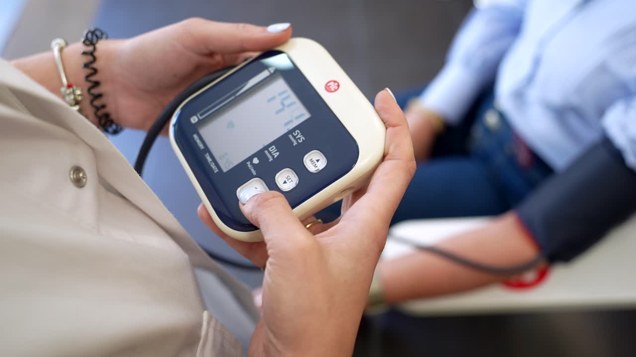 Mani che misurano la pressione sanguigna con un monitor digitale