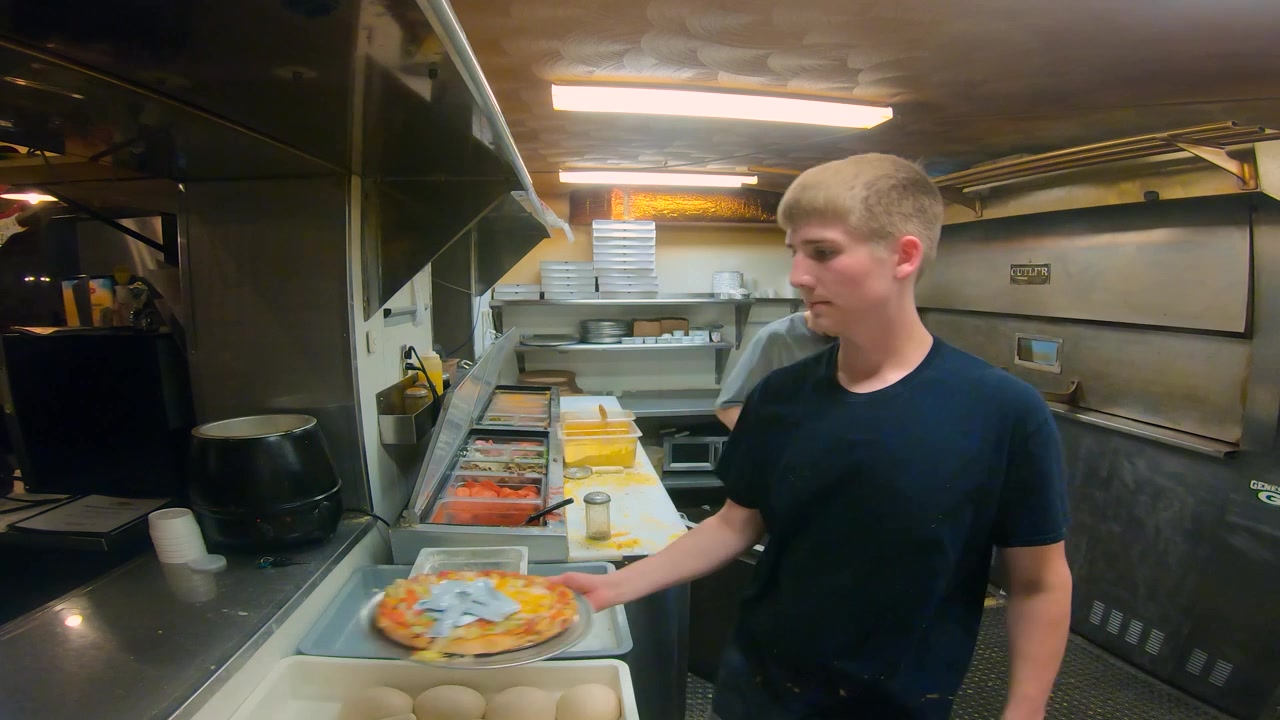 Personale di cucina che prepara pizze nella cucina di una pizzeria-ristorante a conduzione familiare