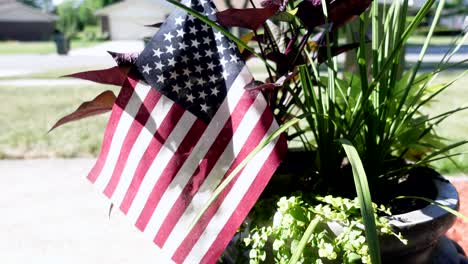 american flag propped up in a flower pot on a bright sunny day, close up