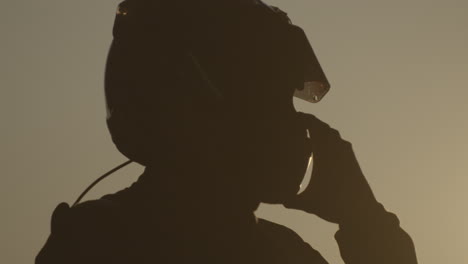 silhouette of a person in a motorcycle helmet against a bright sky