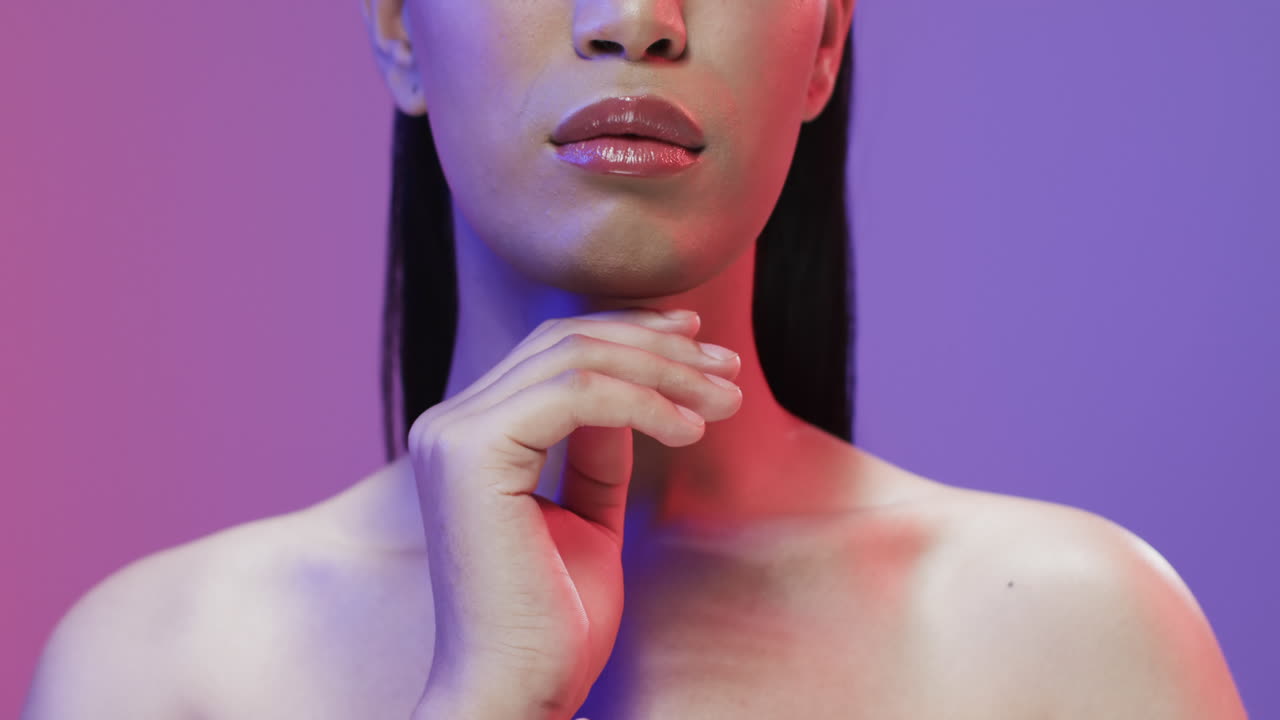 mujer biracial con cabello negro y maquillaje tocando su cara, copia espacio, cámara lenta