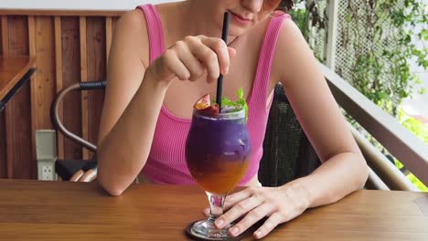 woman enjoying a purple cocktail outdoors