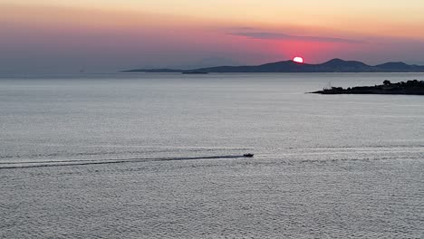 puesta de sol en el mar con un bote de velocidad que pasa | imágenes de un avión no tripulado de una posta de sol en la riviera de atenas