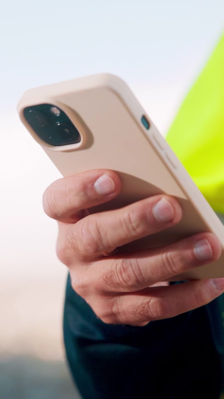 Operaio edile che usa lo smartphone con giubbotto ad alta visibilità