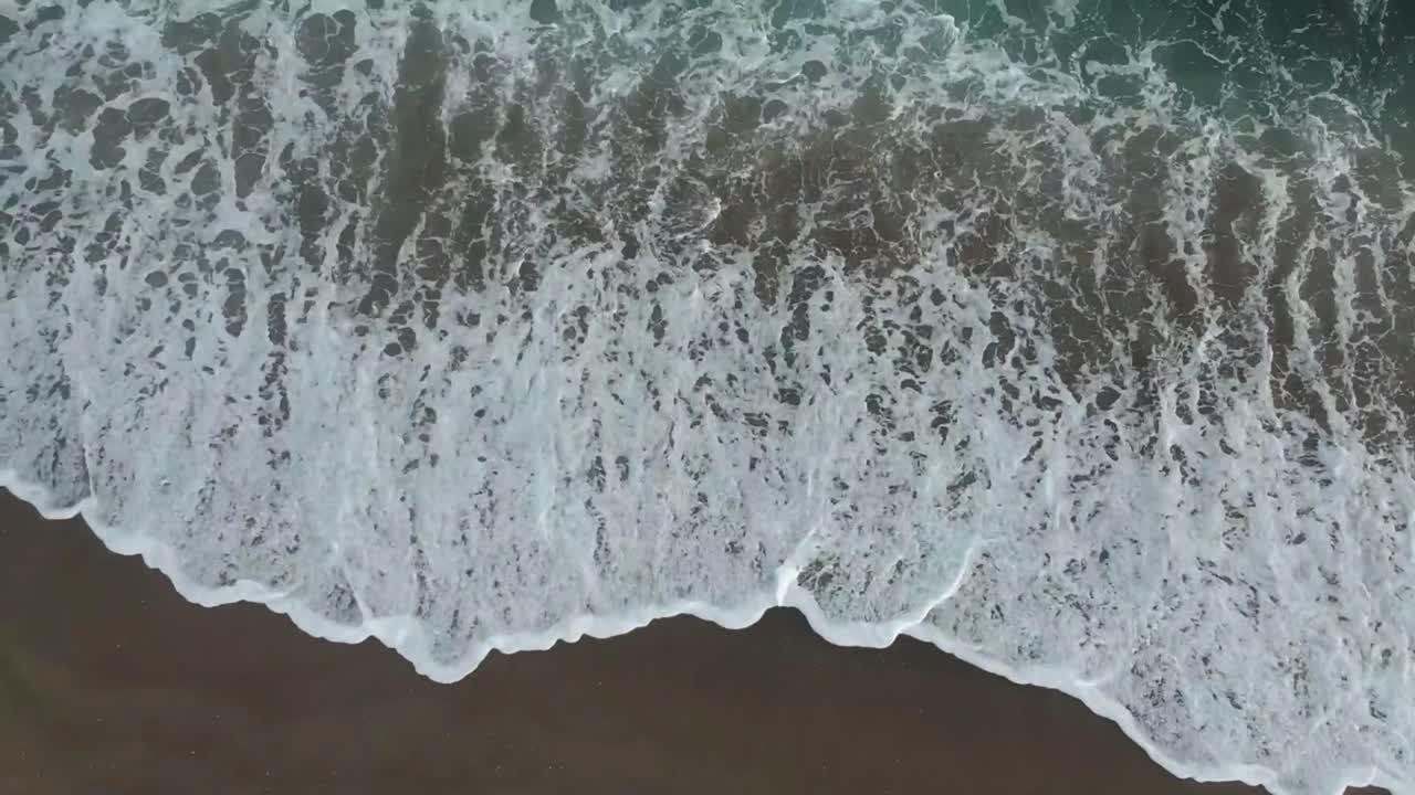 Aerial drone view of a beach with gentle waves on the shore