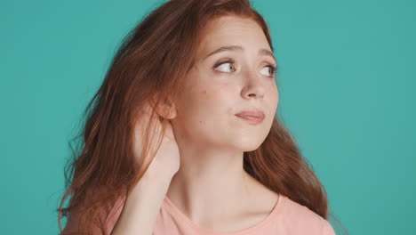 Redheaded-girl-in-front-of-camera-on-turquoise-background.