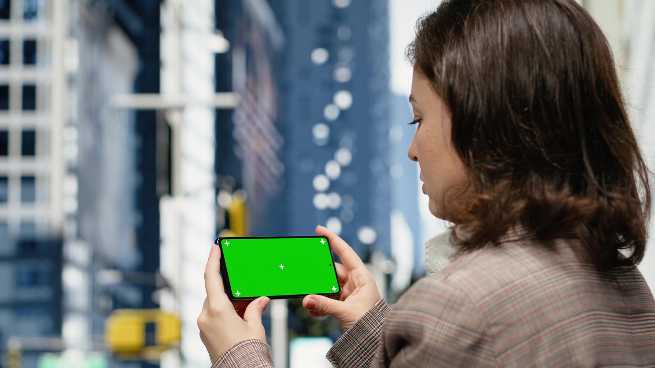 Smartphone mockup con schermo verde usato da un professionista in città.