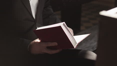 unrecognizable man reading bible while sitting in church