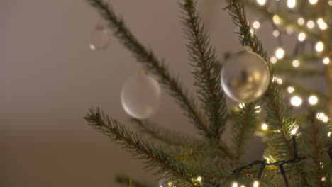 mano colocando un ornamento de plata en un árbol de navidad decorado