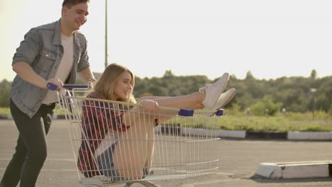 slow motion: a free and cheerful man and woman ride in carts in a supermarket parking lot shouting and raising their hands in the air